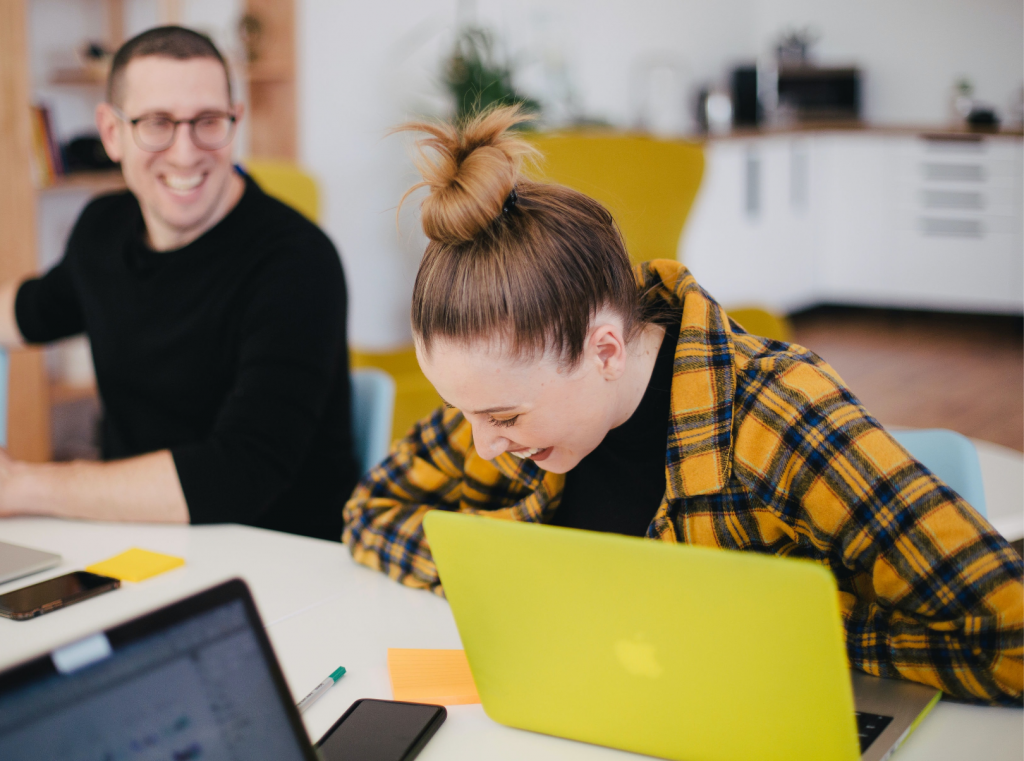 woman laughing with a man while on her laptop